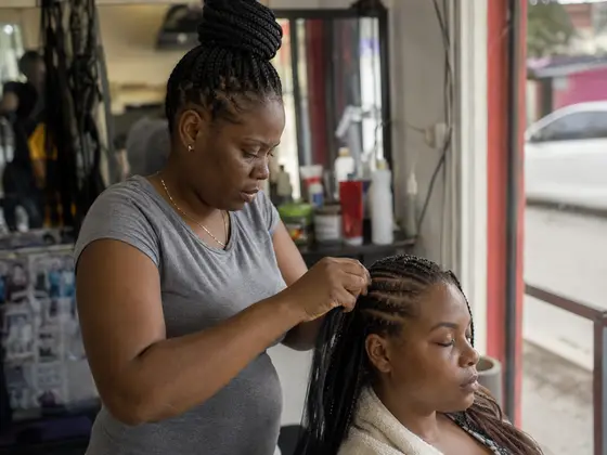 A stylist braiding a client’s hair in a salon in Kingston, Jamaica.