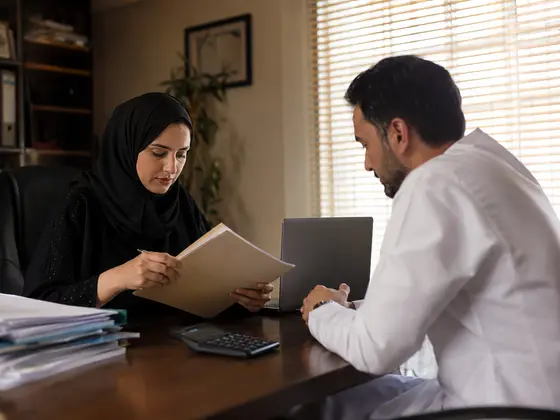 A bookkeeper going through a set of accounts with a client in Dubai.